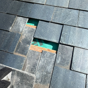Slipped tiles on a slate roof being repaired